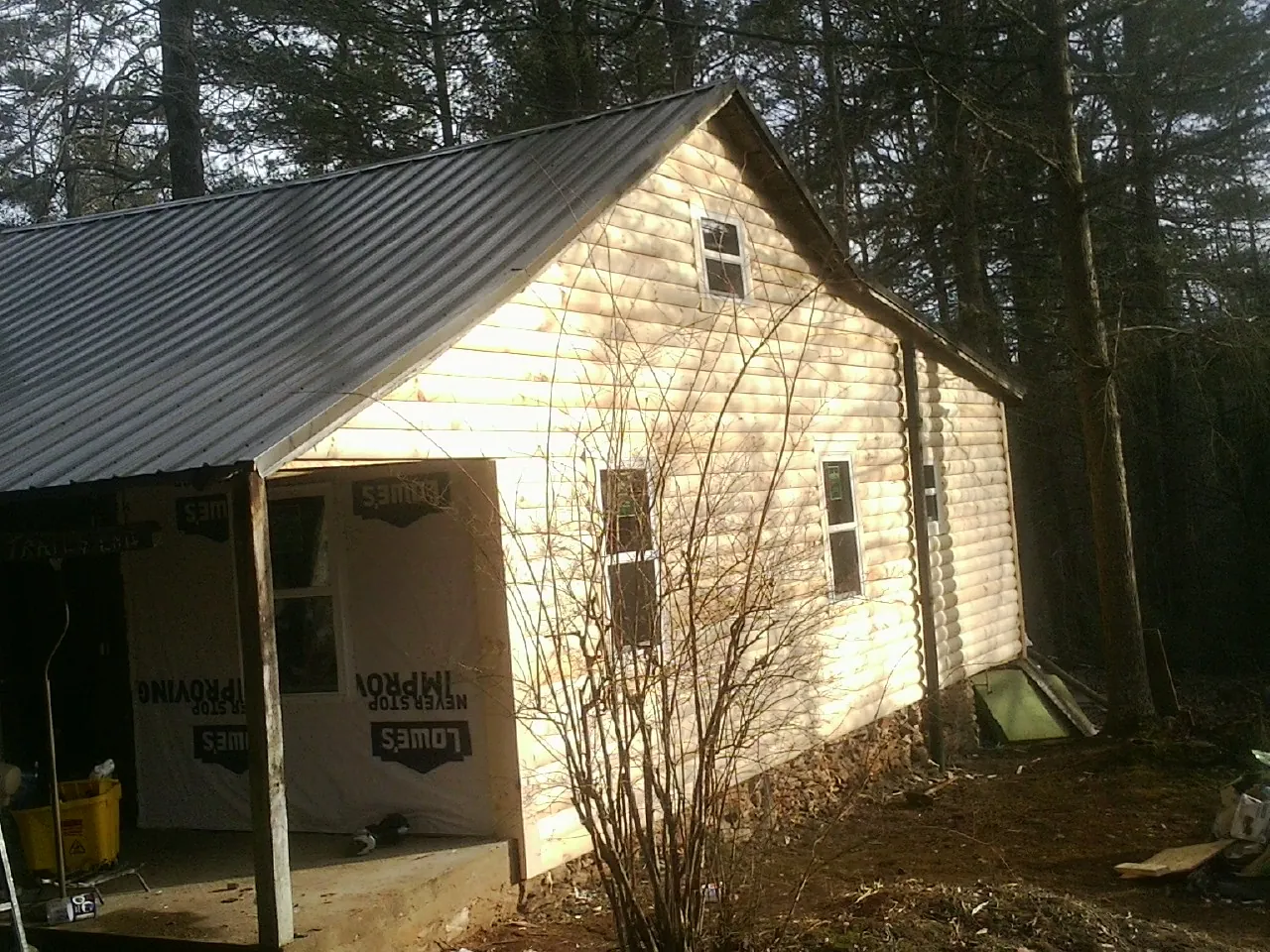Log siding gable end under a dark metal roof edge in Woodbury