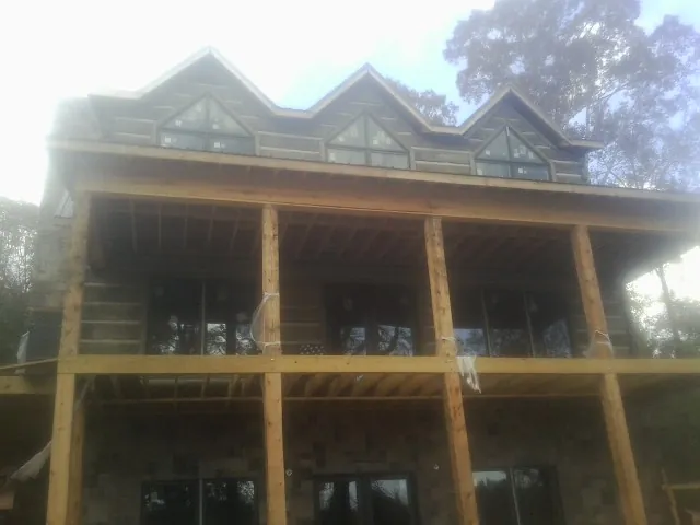Dormers and porch framing on a large log home under construction — Roof Coating work by our crew in Woodbury